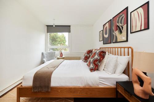 a bedroom with a bed with white sheets and pillows at The Kennington Park Crib - Lovely 2BDR Flat with Garden in London