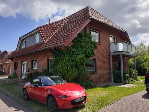un coche rojo estacionado frente a una casa en Balkonwohnung Seestern, en Hooksiel