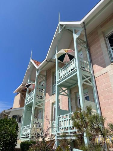 a building with balconies and an umbrella on it at Hôtel Michelet Plage in Soulac-sur-Mer