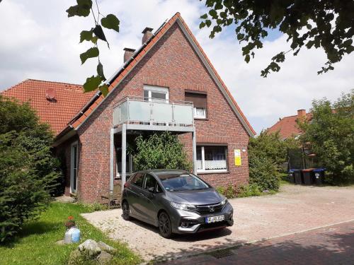 un coche aparcado frente a una casa de ladrillo en Terrassenwohnung Langeoog, en Hooksiel