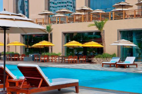 a swimming pool with chairs and tables and umbrellas at The Westin Hyderabad Mindspace in Hyderabad