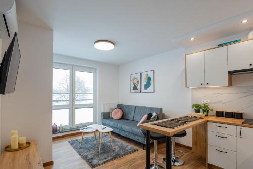 eine Küche und ein Wohnzimmer mit einem Sofa und einem Tisch in der Unterkunft Vip Apartamenty Niecia z klimatyzacja in Rzeszów