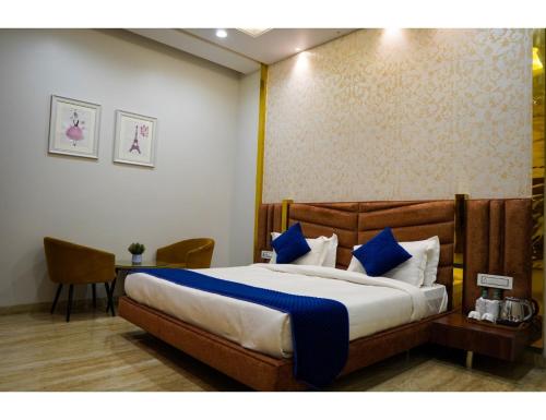 a bedroom with a large bed with blue pillows at The Royal Casa Hotel, Ludhiana in Ludhiana