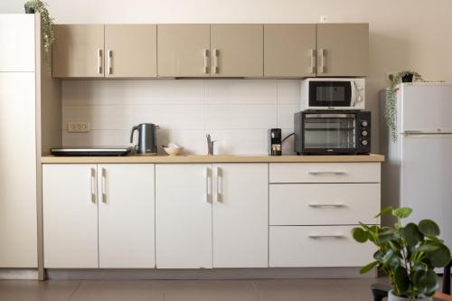 a kitchen with white cabinets and a microwave and a refrigerator at The Printhouse - Downtown Boutique Apartments by Sea N' Rent in Haifa