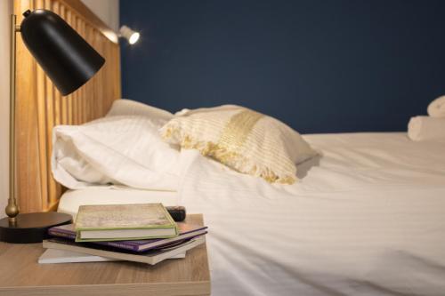 a bed with a table with books and a lamp at The Printhouse - Downtown Boutique Apartments by Sea N' Rent in Haifa