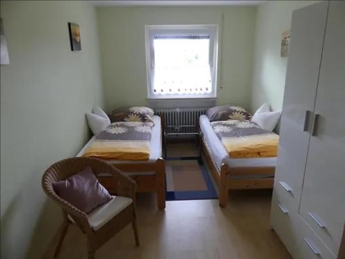 Cette chambre comprend deux lits, une fenêtre et une chaise. dans l'établissement Ferienwohnung Sigrun, à Niedenstein