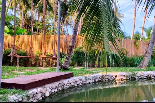 a garden with a pond and palm trees and a fence at Wooden House on lake,city center in Luang Prabang