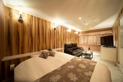 Habitación de hotel con cama y silla en ホテル リベラル 男塾ホテルグループ en Kobe