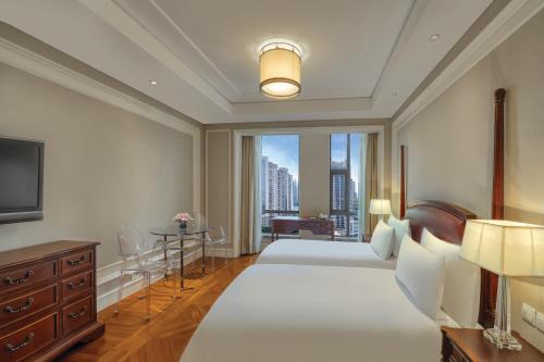 a bedroom with two beds and a large window at Sunrise On The Bund in Shanghai