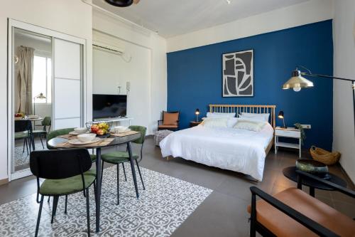 a bedroom with blue walls and a bed and a table at The Printhouse - Downtown Boutique Apartments by Sea N' Rent in Haifa