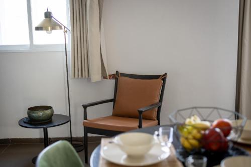 a table with a bowl of fruit and a chair at The Printhouse - Downtown Boutique Apartments by Sea N' Rent in Haifa
