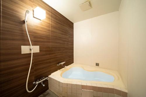 uma banheira na casa de banho com um chuveiro em ホテル リベラル 男塾ホテルグループ em Kobe