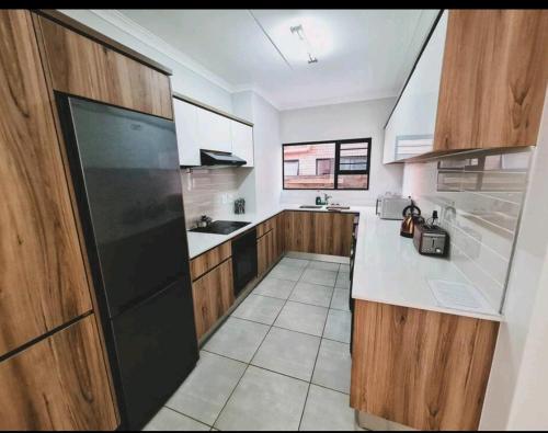 a kitchen with wooden cabinets and a black refrigerator at The Blyde Crystal Lagoon in Pretoria