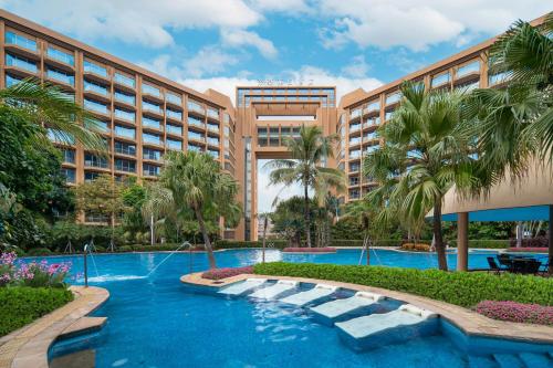 a resort with a swimming pool and palm trees at Dongguan Royal Garden Hotel in Dongguan