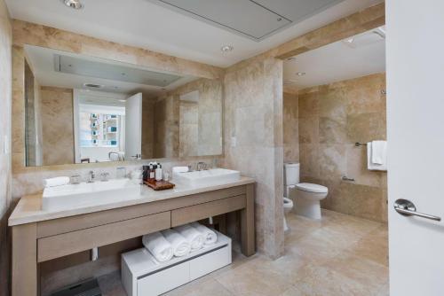 La salle de bains est pourvue de 2 lavabos, de toilettes et d'un miroir. dans l'établissement Oceanview Private Condo at 1 Hotel & Homes -1040, à Miami Beach