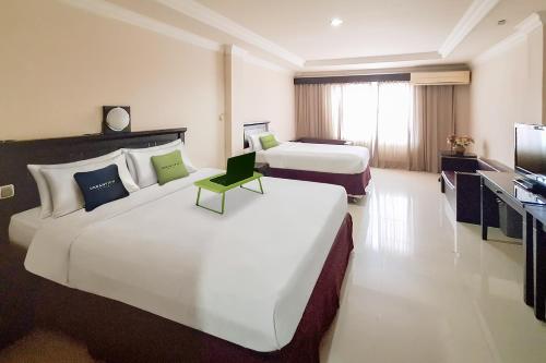 una camera d'albergo con due letti e una televisione di Urbanview Hotel Surya Kahayan Palangkaraya by RedDoorz a Palangkaraya
