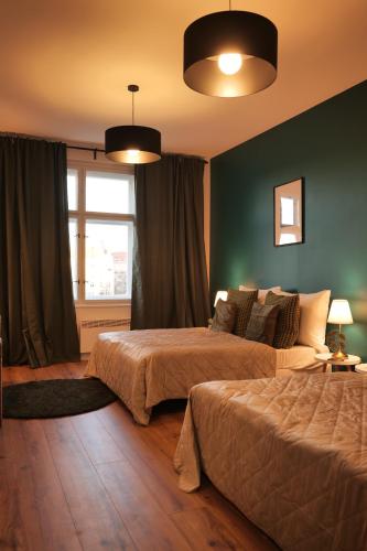 Royal Square View Residence في براغ: سريرين في غرفة نوم مع جدران خضراء