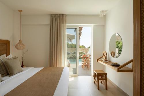 a bedroom with a bed and a view of a patio at Absolute Kiotari Resort in Asklipiḯon
