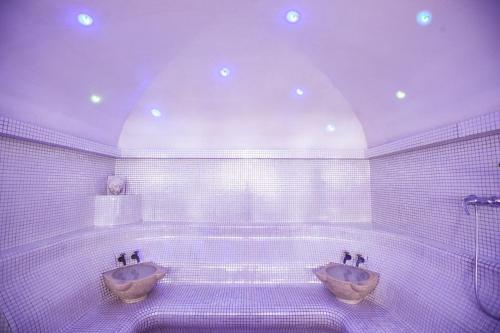 a white tiled bathroom with two sinks and a tub at Sudului ApartHotel in Bucharest