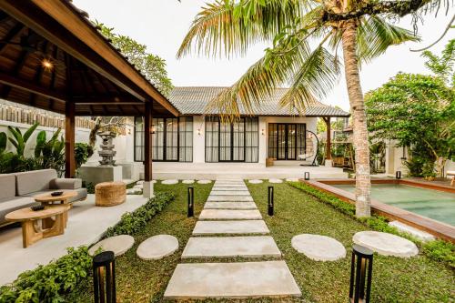een binnenplaats met een zwembad en een huis met een palmboom bij Hijau Villa by EVDEkimi Ubud in Ubud