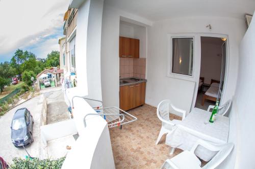 a balcony with white chairs and a kitchen and a car at Guest House Violet in Becici