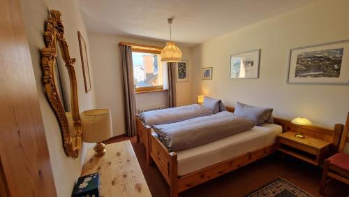 Un dormitorio con una cama, una mesa y un espejo. en Chesa Bellaval, Haus Rizza 2-Zimmerwohnung, en Silvaplana