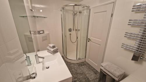 een witte badkamer met een douche en een wastafel bij Chesa Bellaval, Haus Leivra 2-Zimmerwohnung in Silvaplana