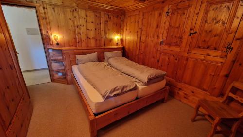 1 dormitorio con 1 cama en una habitación de madera en Chesa Bellaval, Haus Chamuotsch 3 1 2-Zimmerwohnung, en Silvaplana