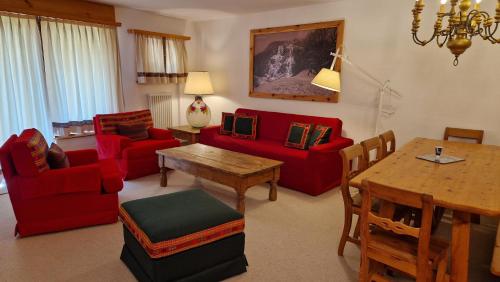 a living room with red furniture and a table at Chesa Bellaval, Haus Chamuotsch 3 1 2-Zimmerwohnung in Silvaplana