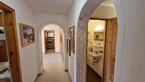 un pasillo con un arco y un lavabo en una habitación en Chesa Bellaval, Haus Chamuotsch 3 1 2-Zimmerwohnung, en Silvaplana