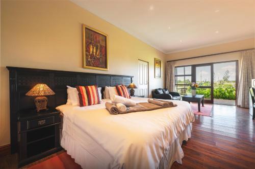 a bedroom with a large bed with white sheets at Temba Private Game Reserve in Grahamstown