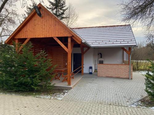 a small cabin with a roof on a brick patio at Ókerka Vendégház in Csesztreg