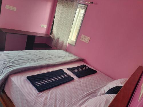 a bedroom with two beds and a pink wall at Supritha Homestay Hampi in Hampi