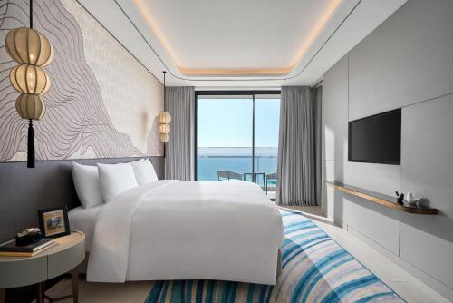 a hotel room with a white bed and a television at voco Ma Belle Danang by IHG in Da Nang