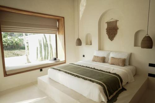 um quarto com uma cama grande e uma janela em VILLA ROSADO - Canggu's Hidden Gem: beautiful boutique Villa em Canggu