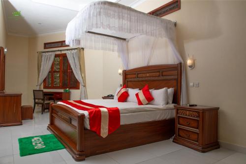 una camera con letto in legno e cuscini rossi e bianchi di Miika Eco Resort Hotel a Hoima
