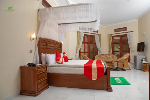 a bedroom with a canopy bed with red pillows at Miika Eco Resort Hotel in Hoima