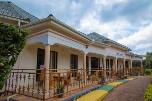 a house with a balcony with tables and chairs at Miika Eco Resort Hotel in Hoima