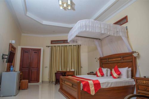 a bedroom with a large wooden bed with red pillows at Miika Eco Resort Hotel in Hoima