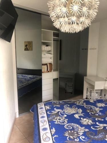 Un dormitorio con una cama azul y una lámpara de araña. en Chez Peter, en La Grande-Motte