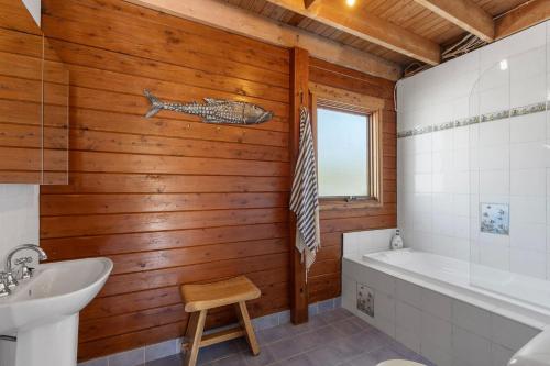 a bathroom with a wooden wall with a fish on the wall at The Beach Haven in Bawley Point