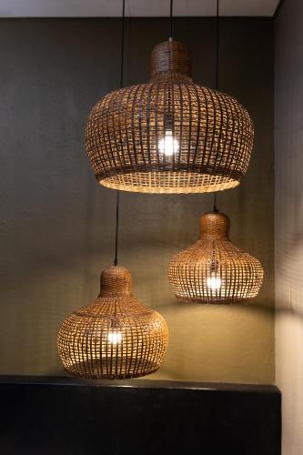 a group of three wicker lights hanging from a wall at Wasabi in Canggu