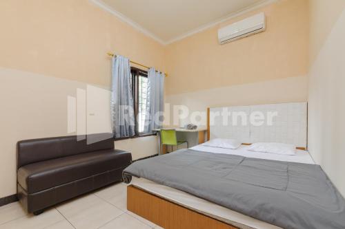 1 dormitorio con 1 cama y 1 silla en Karawaci Taman Permata Tiga Mitra RedDoorz en Binong