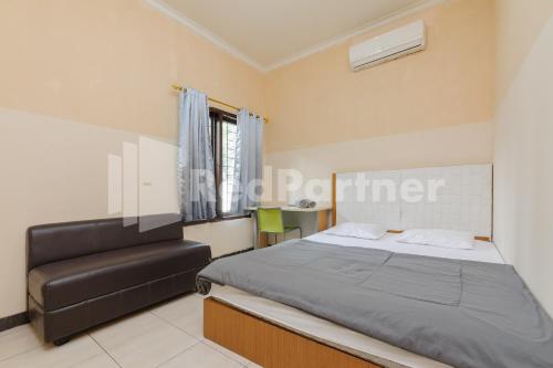 a bedroom with a bed and a chair at Karawaci Taman Permata Tiga Mitra RedDoorz in Binong