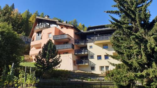 a large apartment building with balconies and trees at Chesa Bellaval, Haus Leivra 2 1 2-Zimmerwohnung in Silvaplana