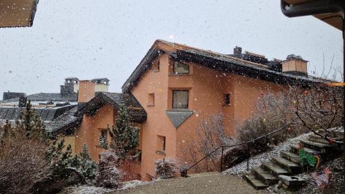 an old brick building with snow falling on it at Chesa Bellaval, Haus Leivra 2 1 2-Zimmerwohnung in Silvaplana