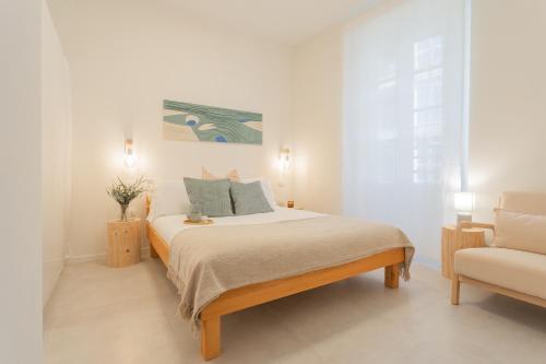 a white bedroom with a bed and a chair at Enchanted Como Lake - City Apartment 2 by Rent All Como in Como