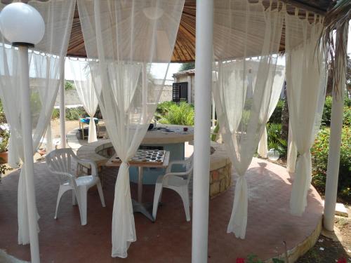 a gazebo with white curtains and a table and chairs at Ville Alba & Azzurra in Polignano a Mare