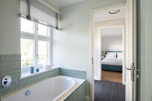 La salle de bains est pourvue d'une baignoire, d'une fenêtre et d'un lit. dans l'établissement Ferienwohnung Lotte, à Waabs