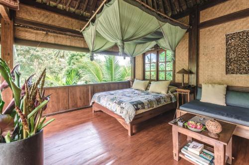 a bedroom with a bed and a large window at Bali Eco Stay in Blimbing